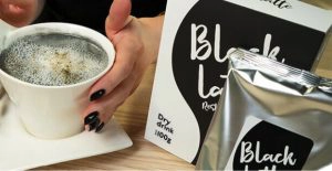 vrouw houdt black latte koffie vast met verpakking ernaast
