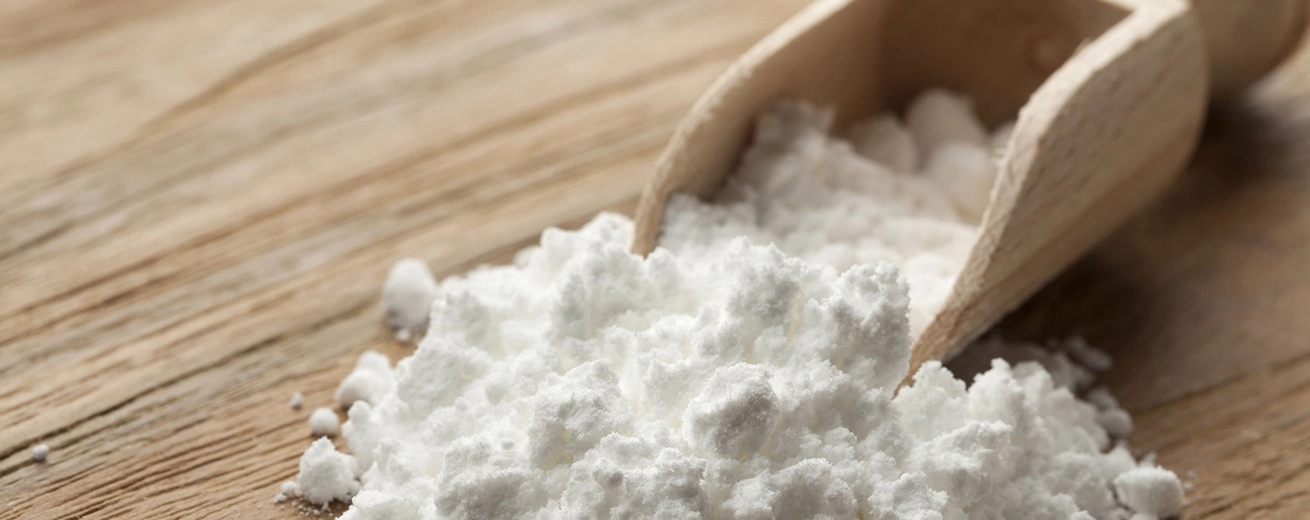 Wat Is E621? (MSG / Vetsin / Glutamaat ) + 6 Bijwerkingen Houten lepel met Vet-sin op witte achtergrond