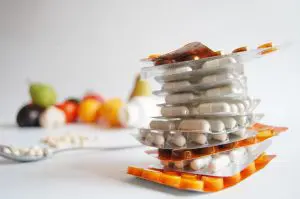 verschillende soorten tabletten op elkaar gestapeld met fruit op de achtergrond
