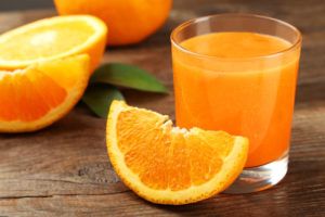 Glas sinaasappelsap met gesneden sinaasappel op houten tafel