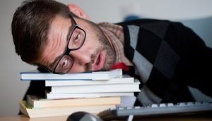 Vermoeide man ligt op een stapel boeken