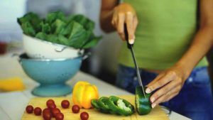 vrouw snijdt groene paprika in stukjes