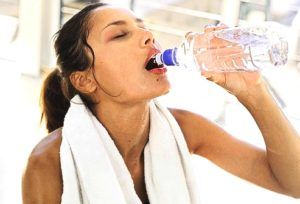 zwetende vrouw drinkt fles met water